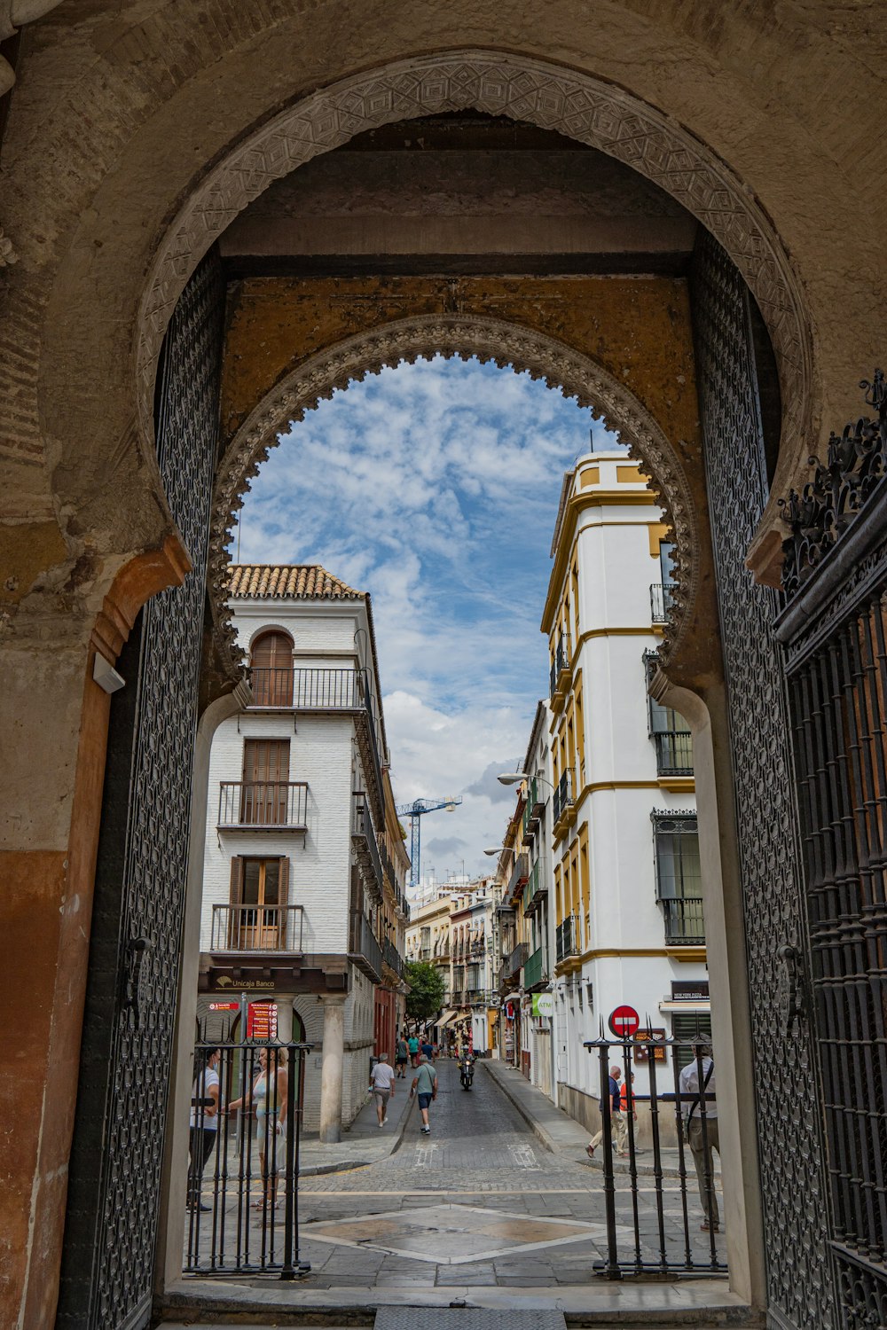 a gated entrance to a street with people walking on it