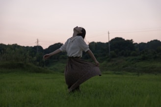 A serene image of a woman standing in a field, arms outstretched to the sky, symbolizing freedom and healing.