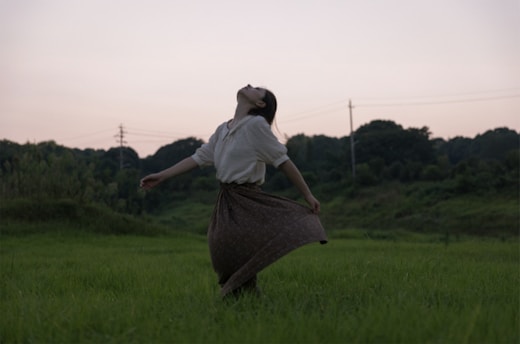 A serene image of a woman standing in a field, arms outstretched to the sky, symbolizing freedom and healing.