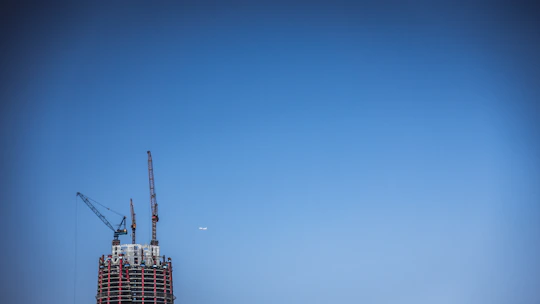 Architects and developers reviewing blueprints on a construction site with cranes in the background.
