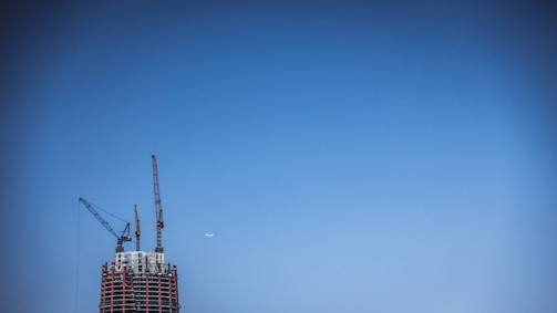 Wide aerial shot of construction site monitored by drone under clear blue sky.