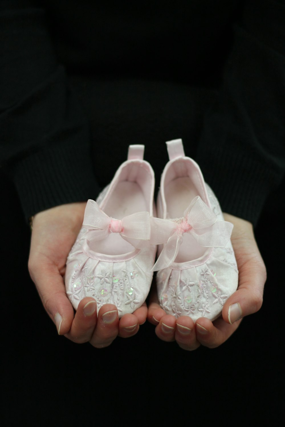 a person holding two pairs of white shoes