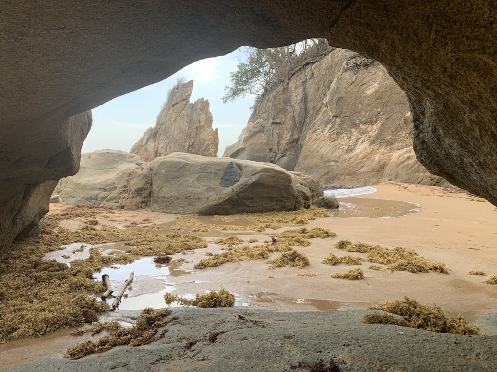 a view of some rocks and water from inside a cave