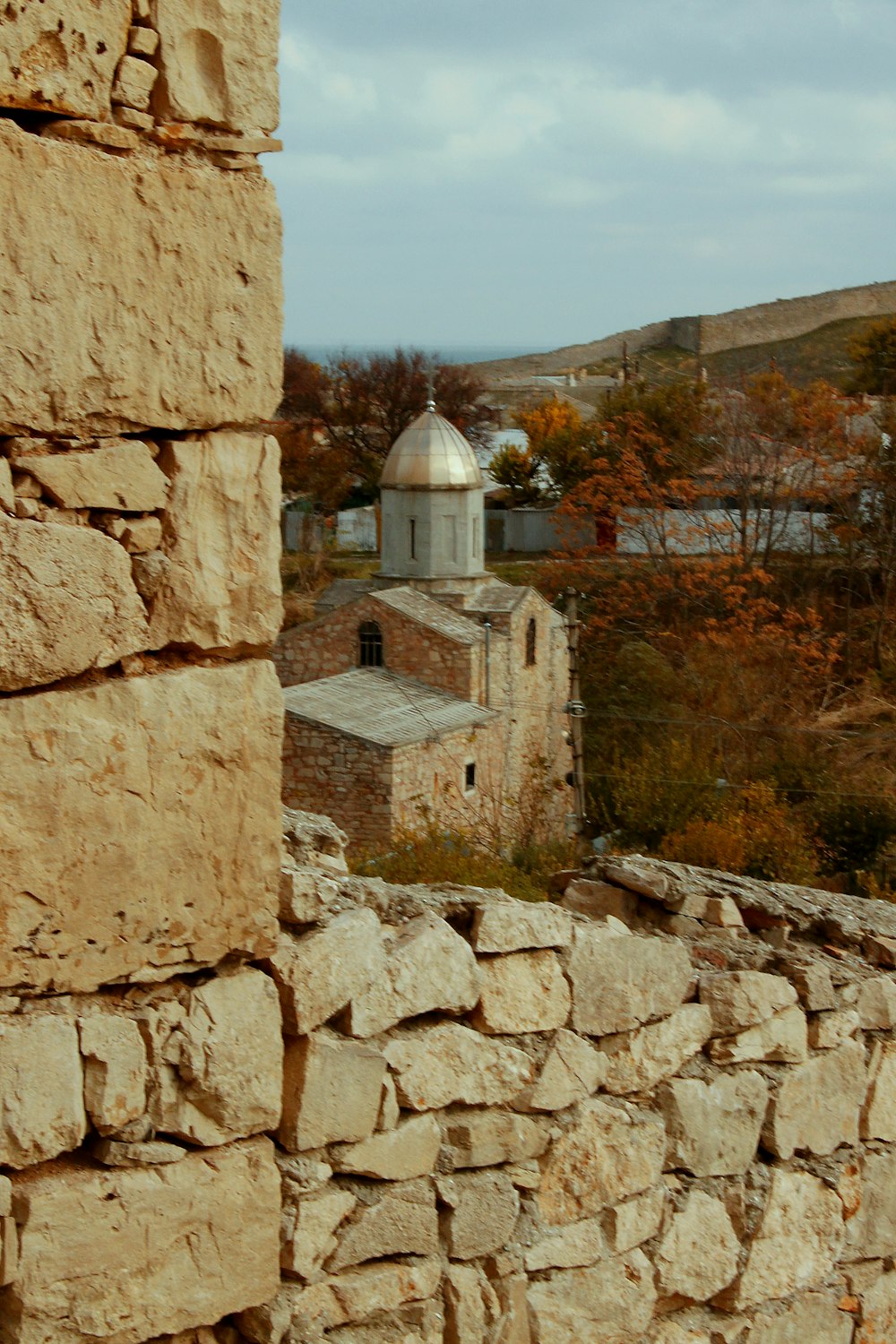 a stone wall with a building in the background