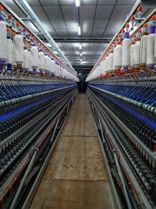 a large room with rows of machines and spools of thread