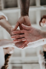 Several hands of diverse skin tones coming together in a gesture of unity and teamwork.