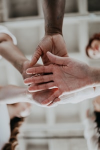 Several hands of diverse skin tones coming together in a gesture of unity and teamwork.