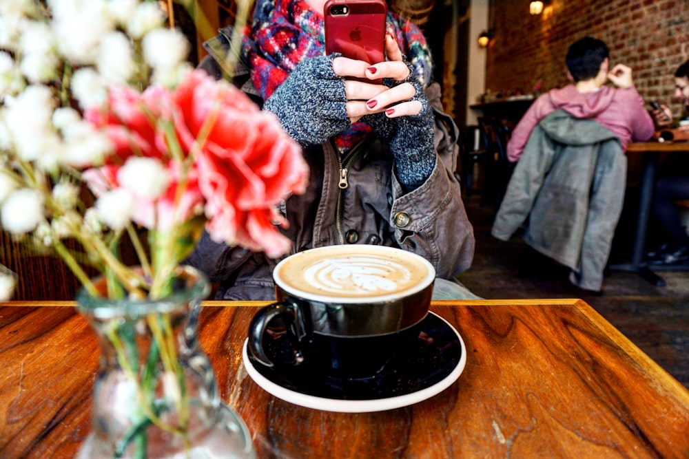 a person taking a picture of a cup of coffee