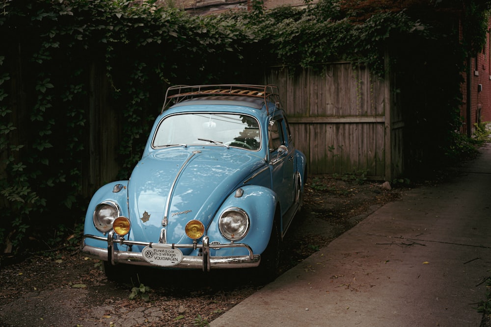 a blue car parked in front of a wooden fence