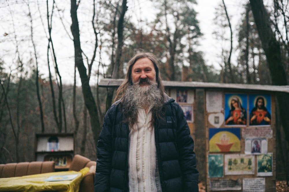 a man with a long beard standing in the woods