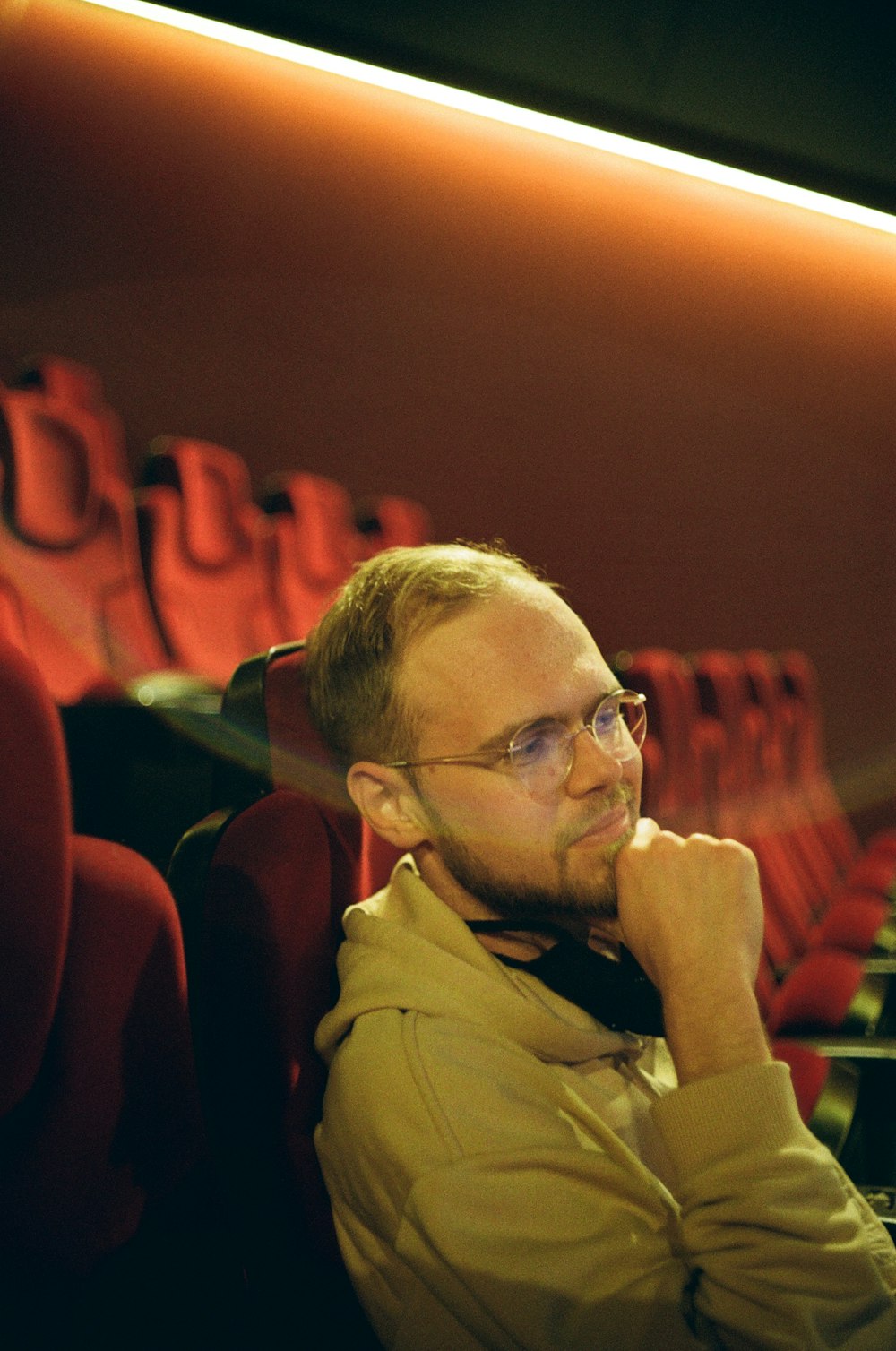 a man with glasses sitting in a red chair