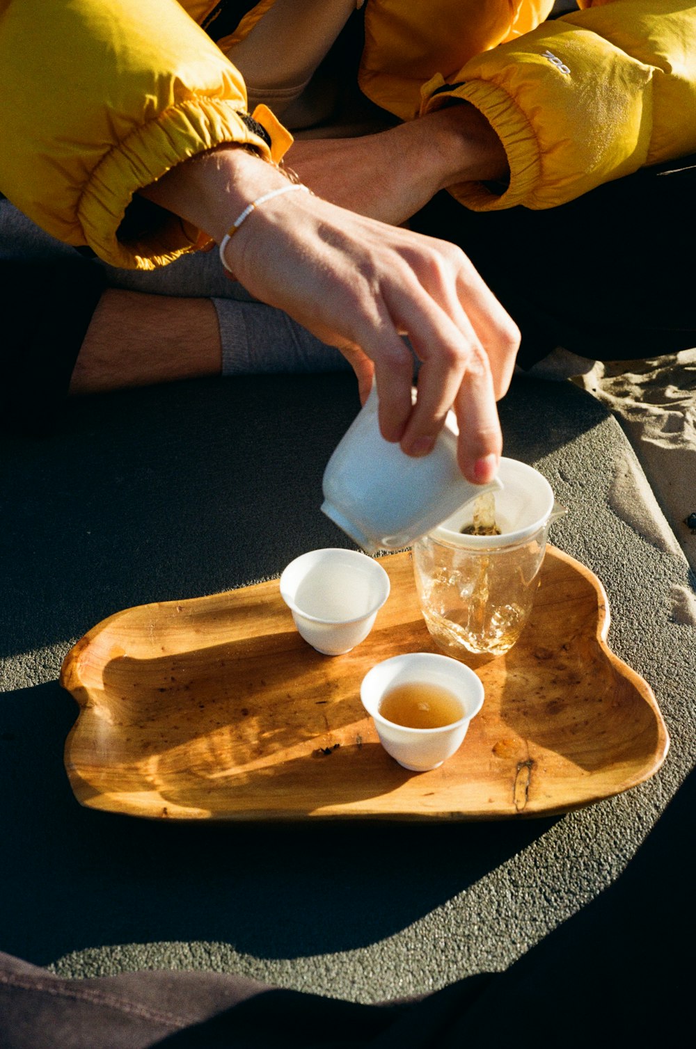 a person pours tea into small cups on a tray