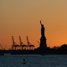 the statue of liberty is silhouetted against a sunset