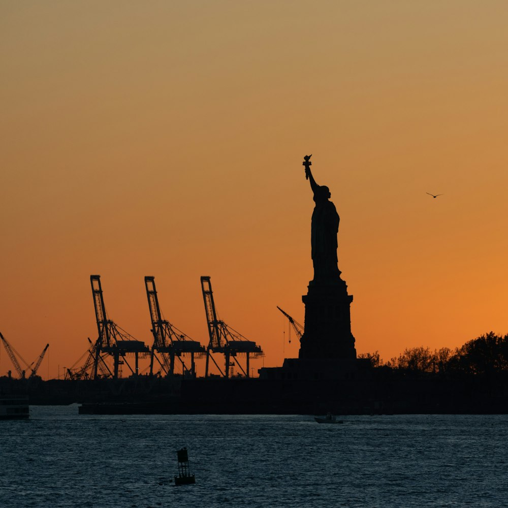 a estátua da liberdade é silhuetada contra um pôr do sol