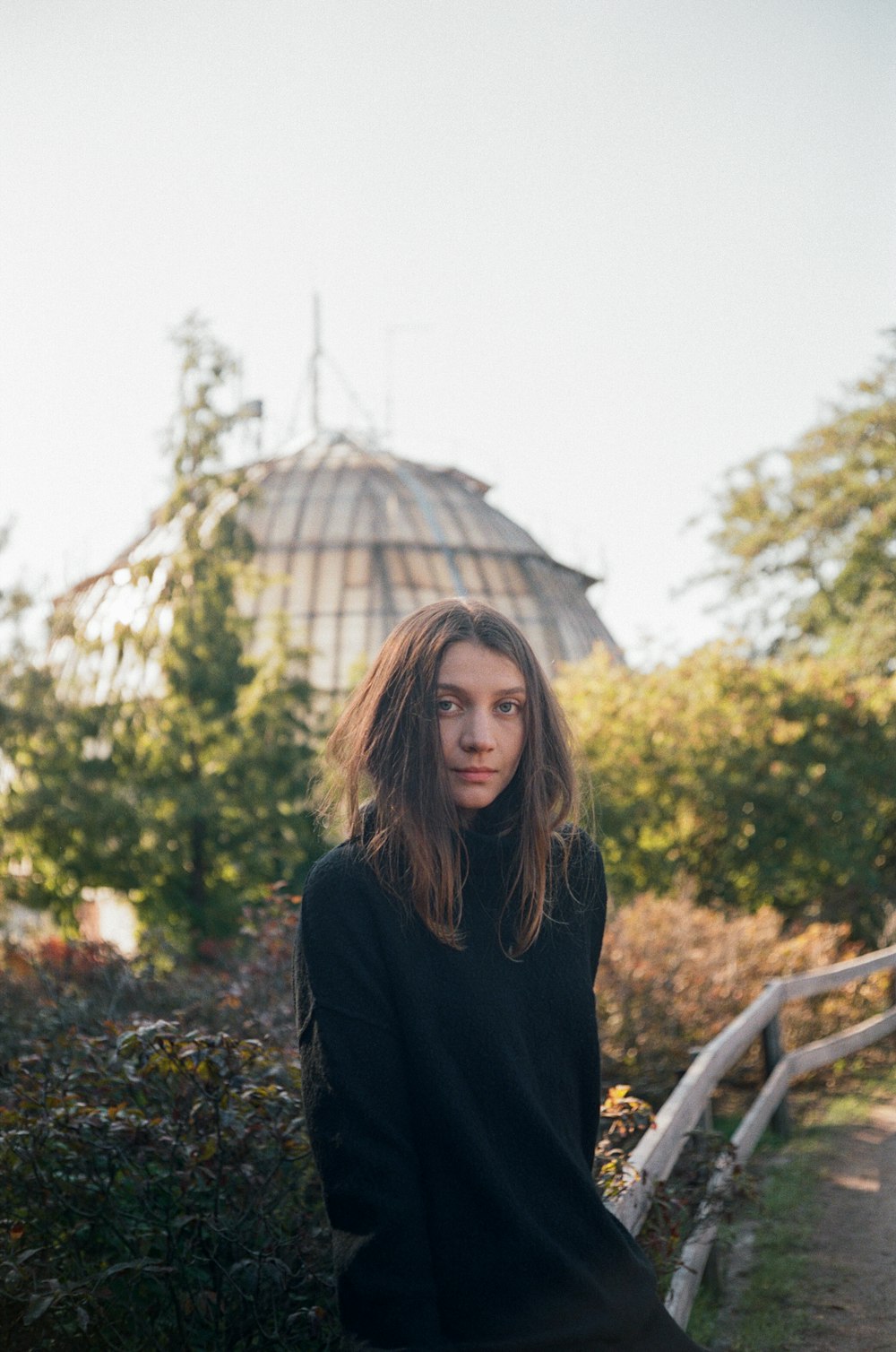 a woman standing in front of a wooden fence