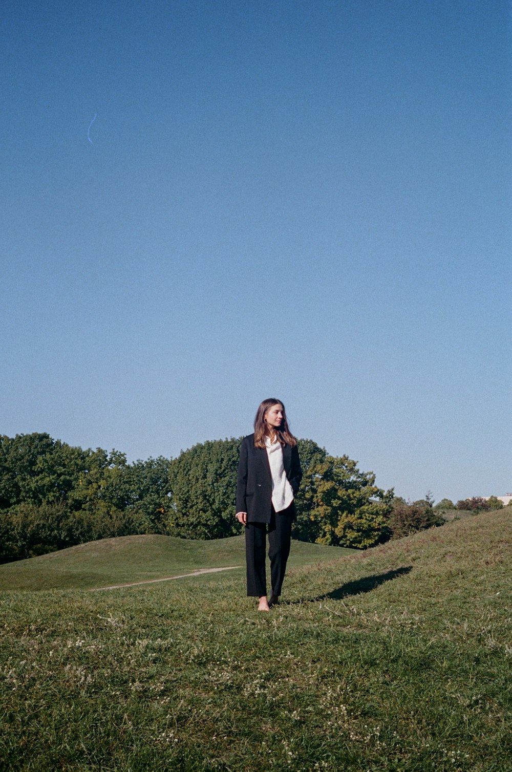 a woman standing in a field with a kite in the sky