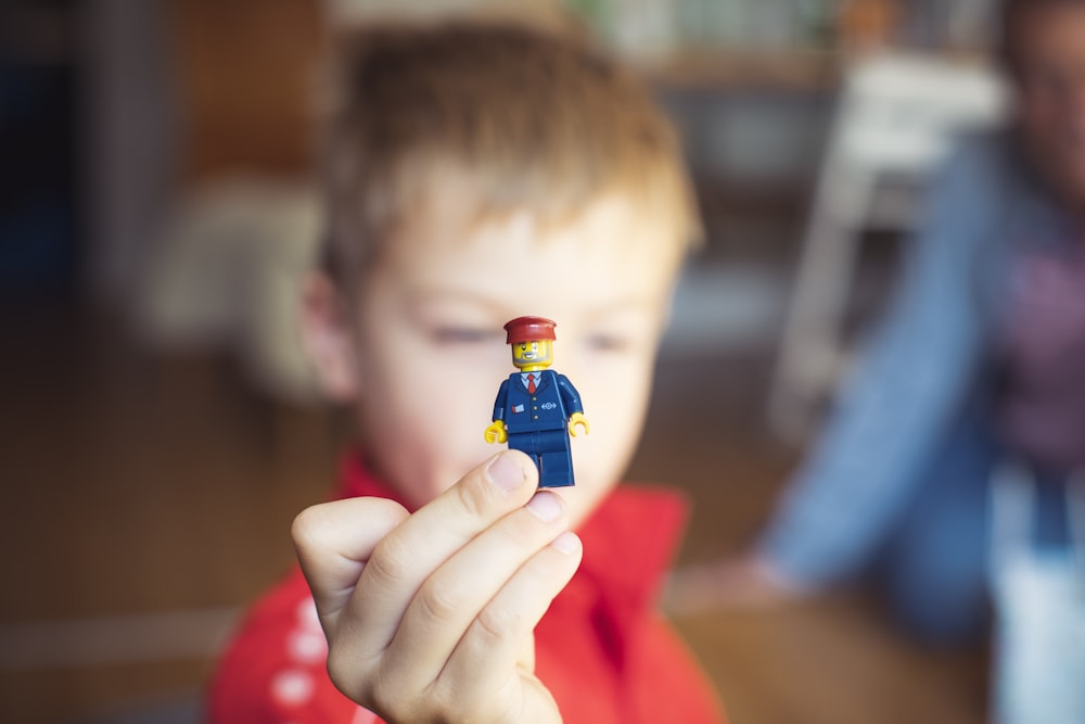 a little boy holding a tiny toy in his hand