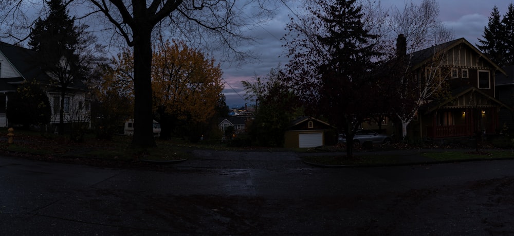 a dark street with houses and trees in the background