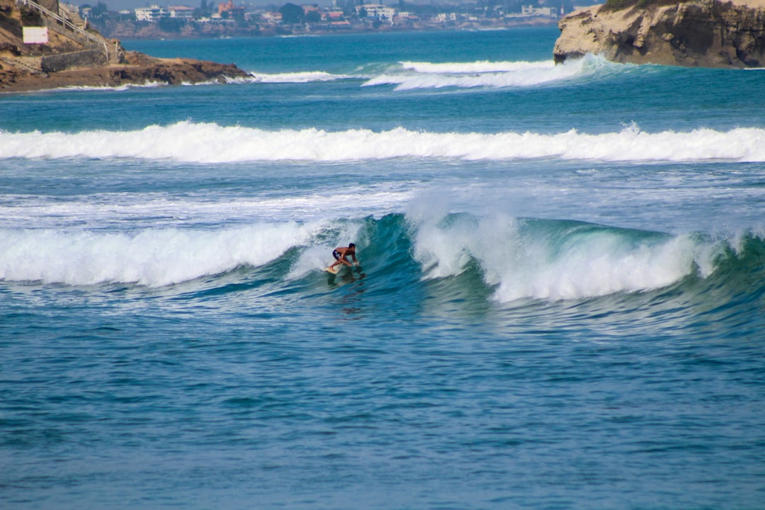 a man riding a wave on top of a surfboard,