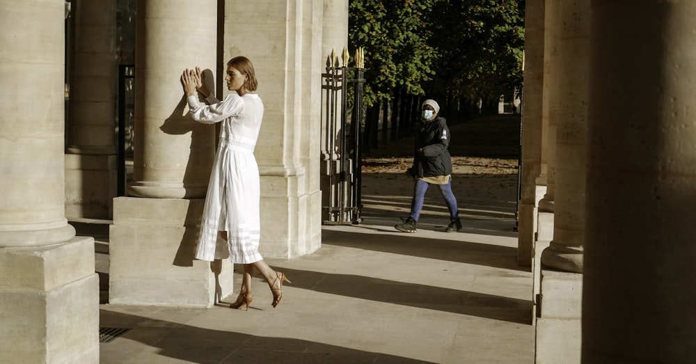 a woman in a white dress is standing outside