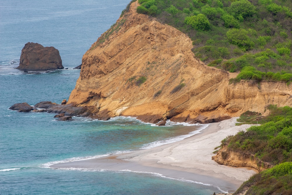 a large rock outcropping on the side of a beach