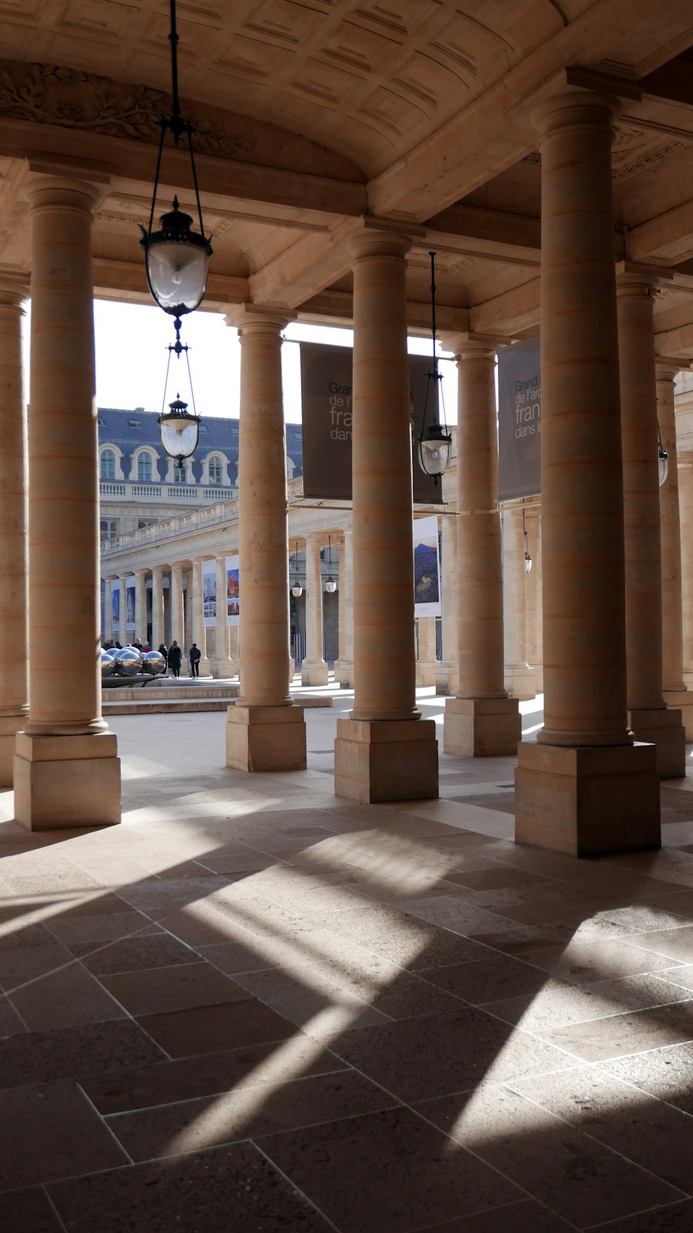 a row of pillars in a building with a clock hanging from the ceiling