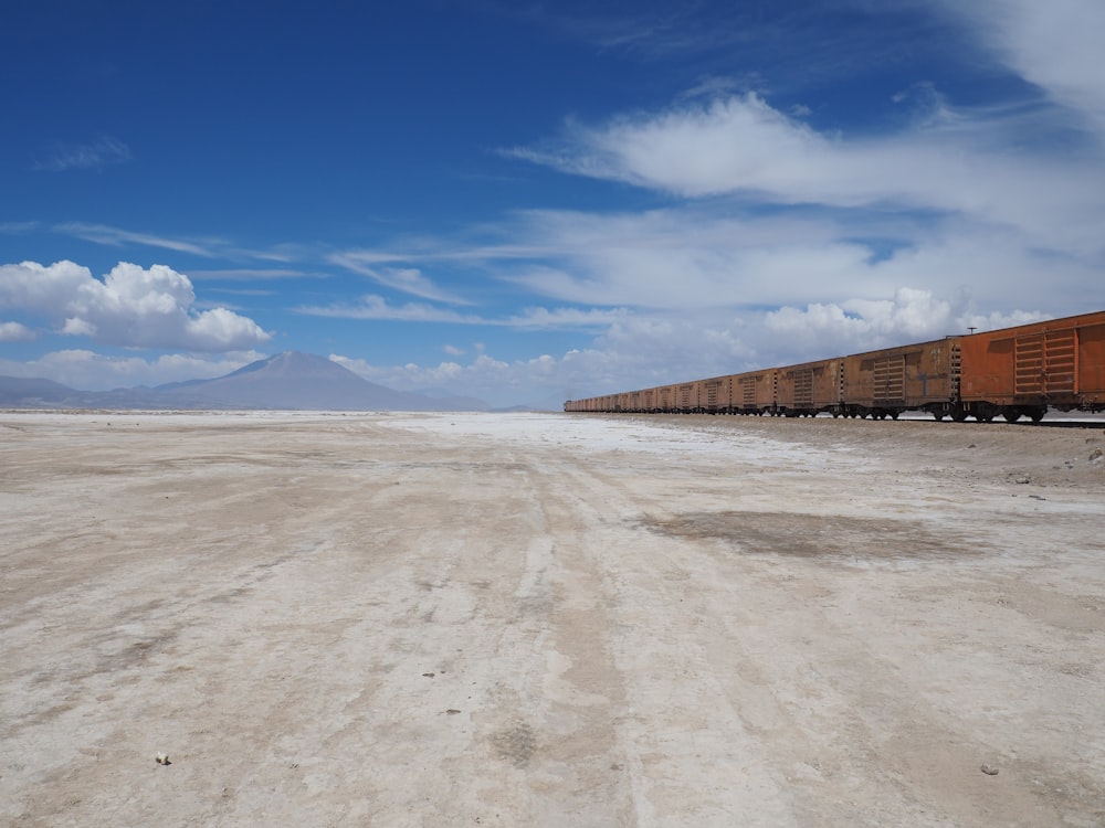 a long train traveling through a desert under a blue sky