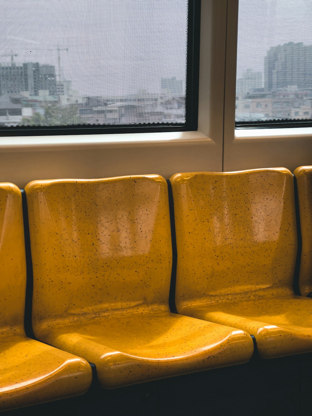 a row of yellow seats sitting next to a window