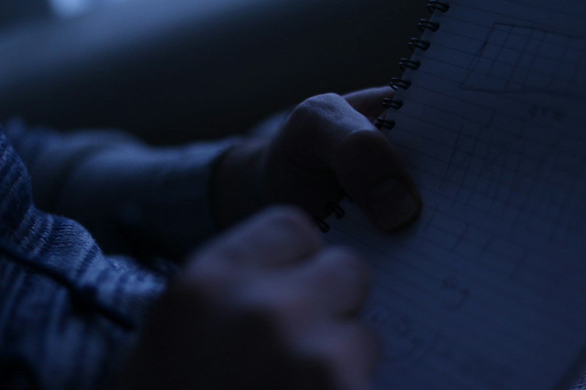 A person holding a notebook, ready to jot down parent-teacher conference questions during a meeting.