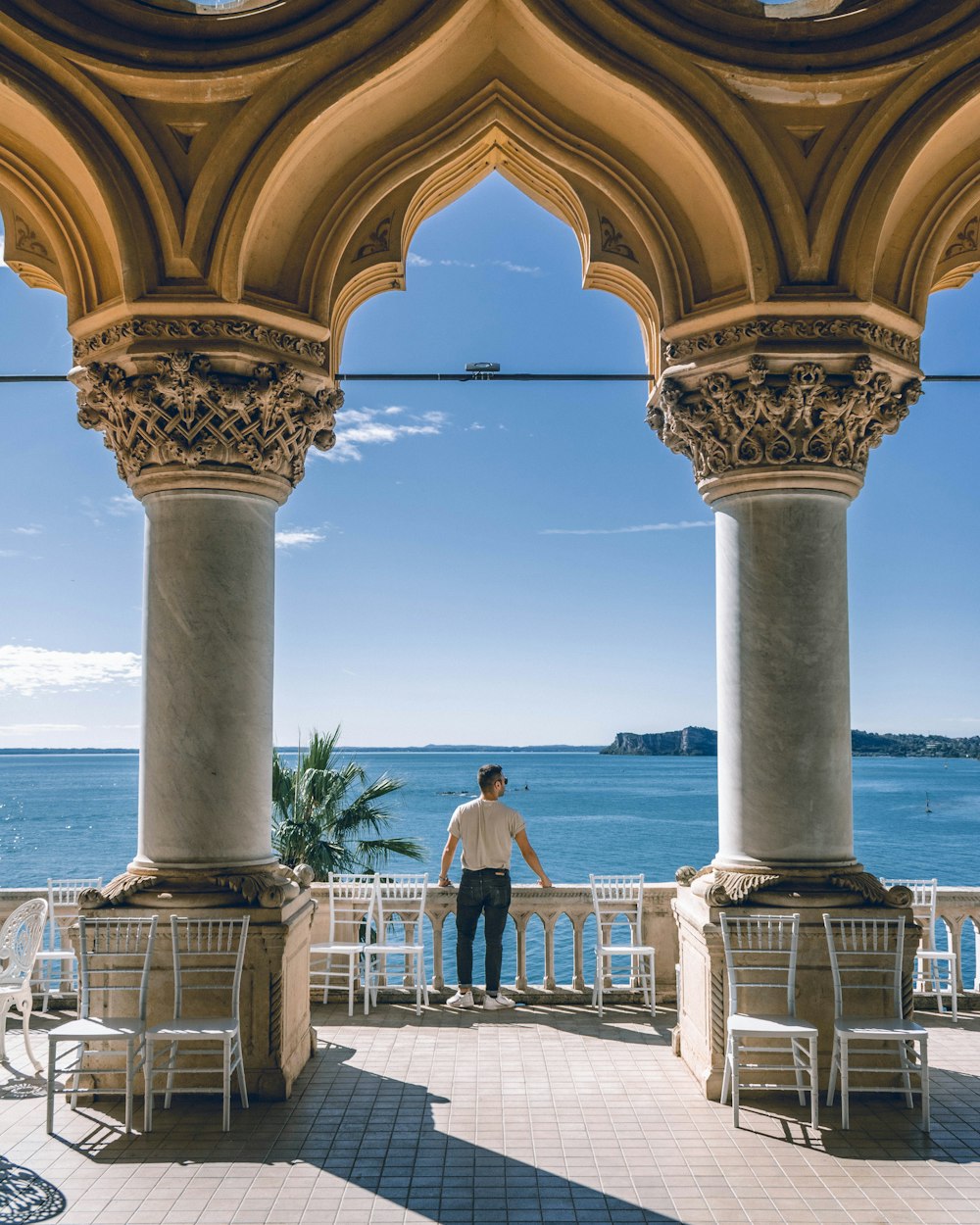 a man standing on a balcony next to a body of water