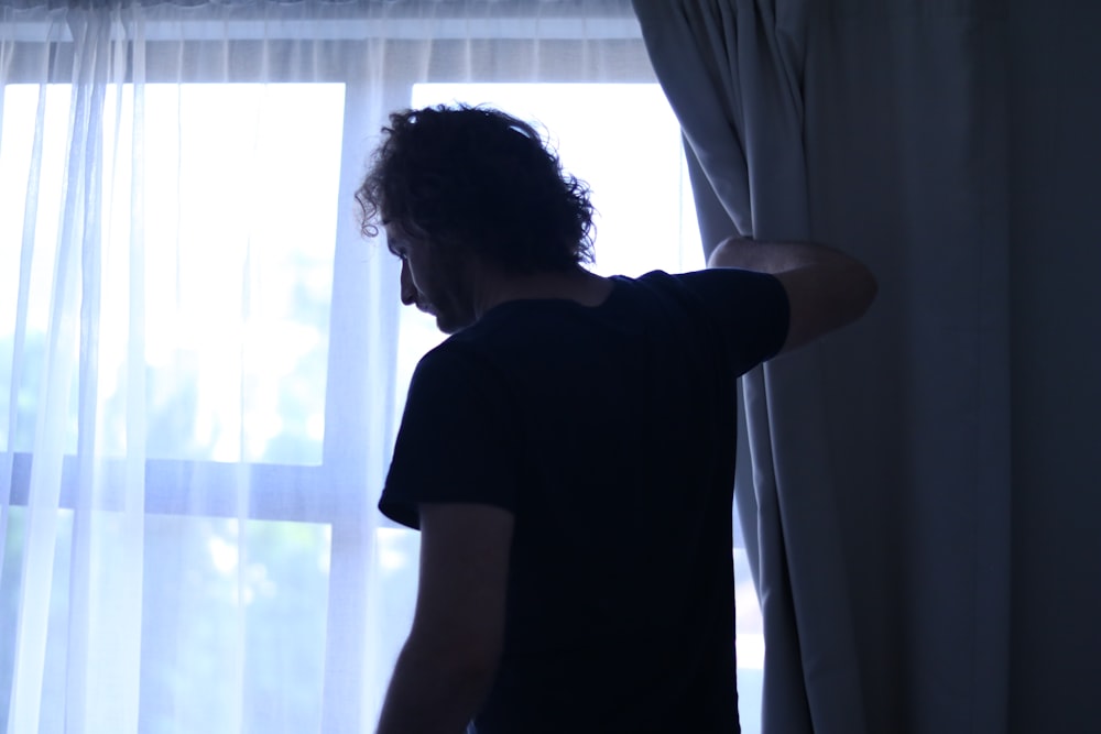 a man standing in front of a window next to a curtain