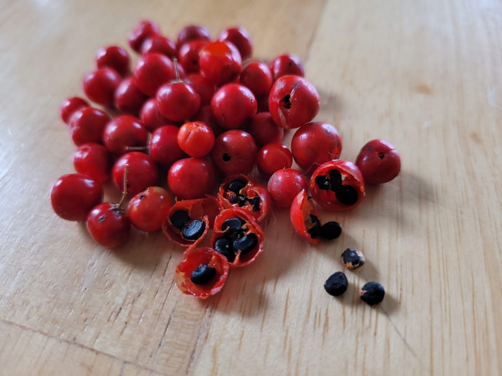 a pile of red fruit sitting on top of a wooden table