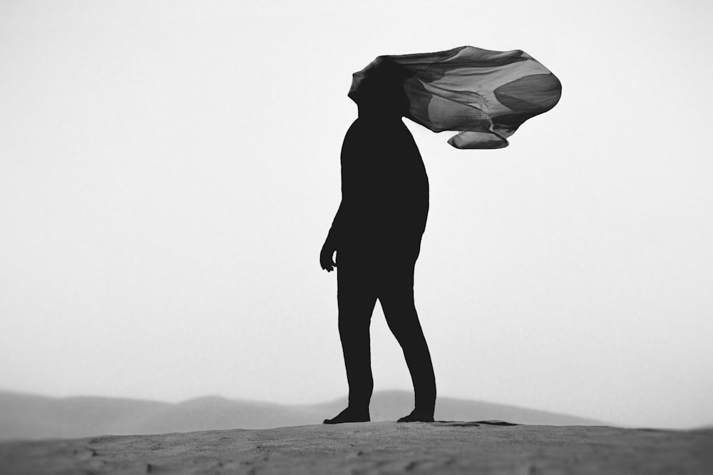 a black and white photo of a person holding a kite