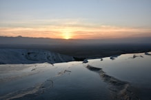 the sun is setting over a snowy mountain