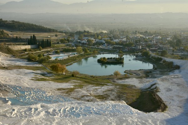 White travertine terraces above the village and its lake — Pamukkale, Turkey