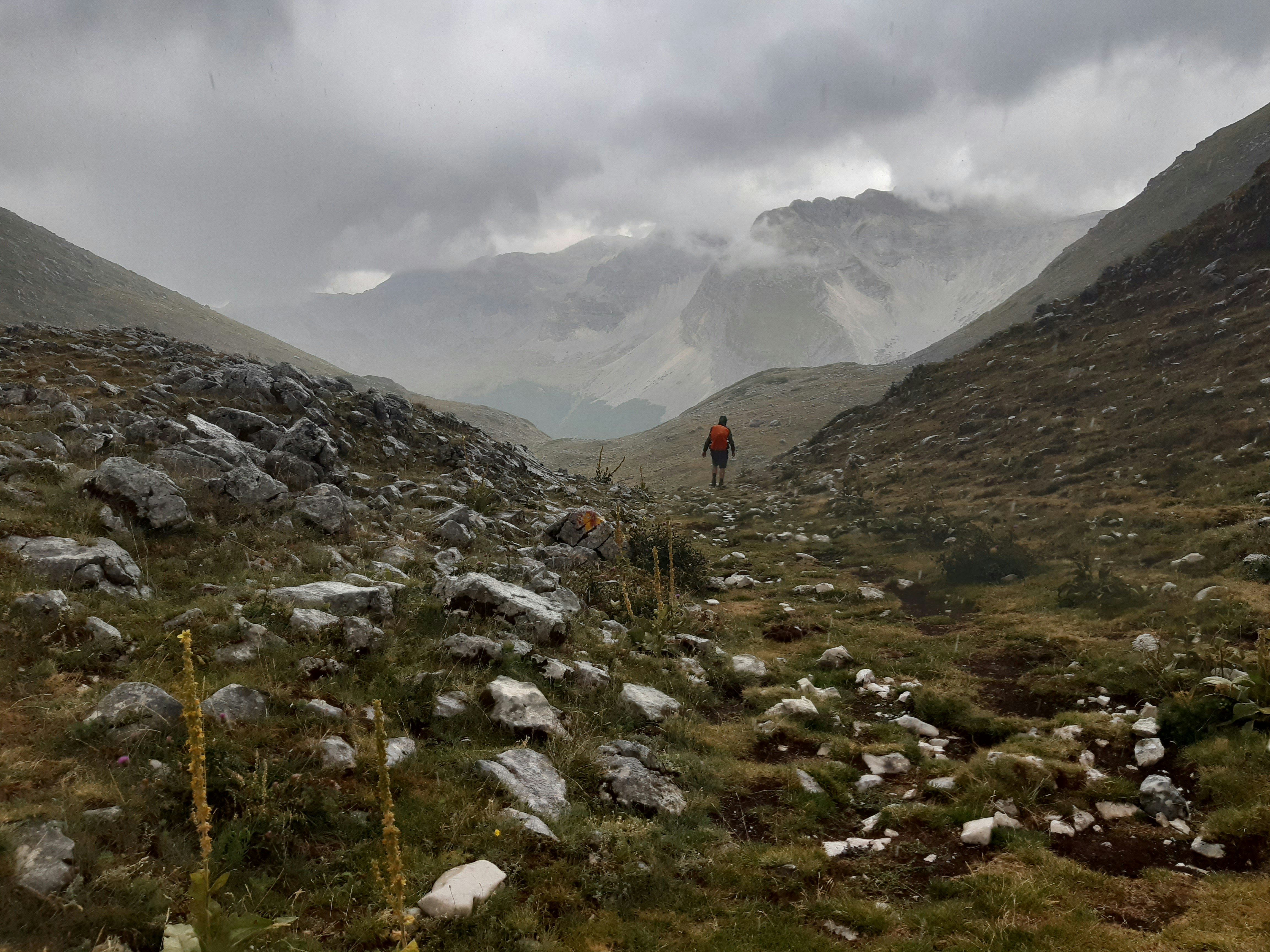 a man hiking up a mountain in the rain, 