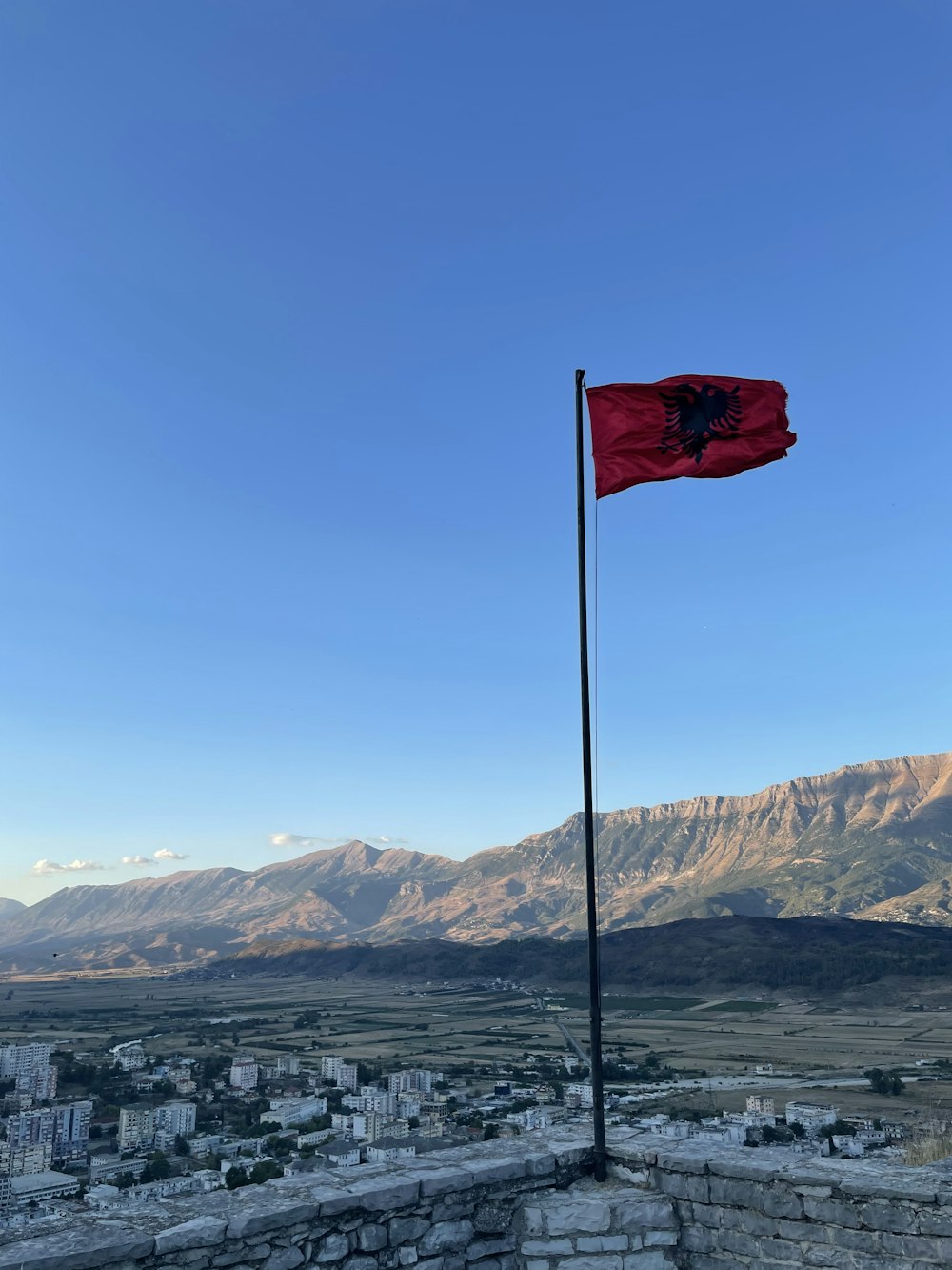 a red flag on top of a building with mountains in the background