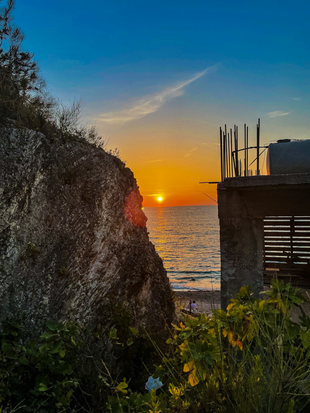 the sun is setting over the ocean from a cliff