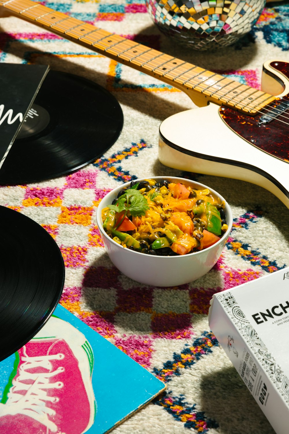 Un tazón de comida sentado encima de una mesa junto a una guitarra