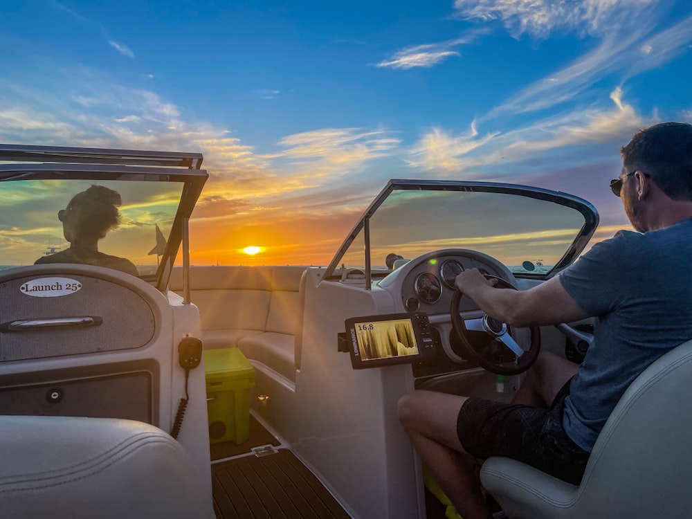 a man driving a boat with the sun setting in the background
