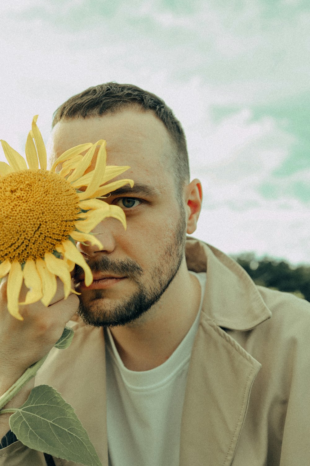 a man holding a sunflower up to his face