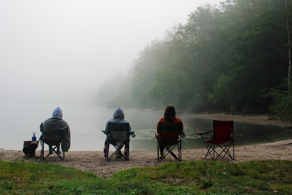 a couple of people sitting in lawn chairs on a beach