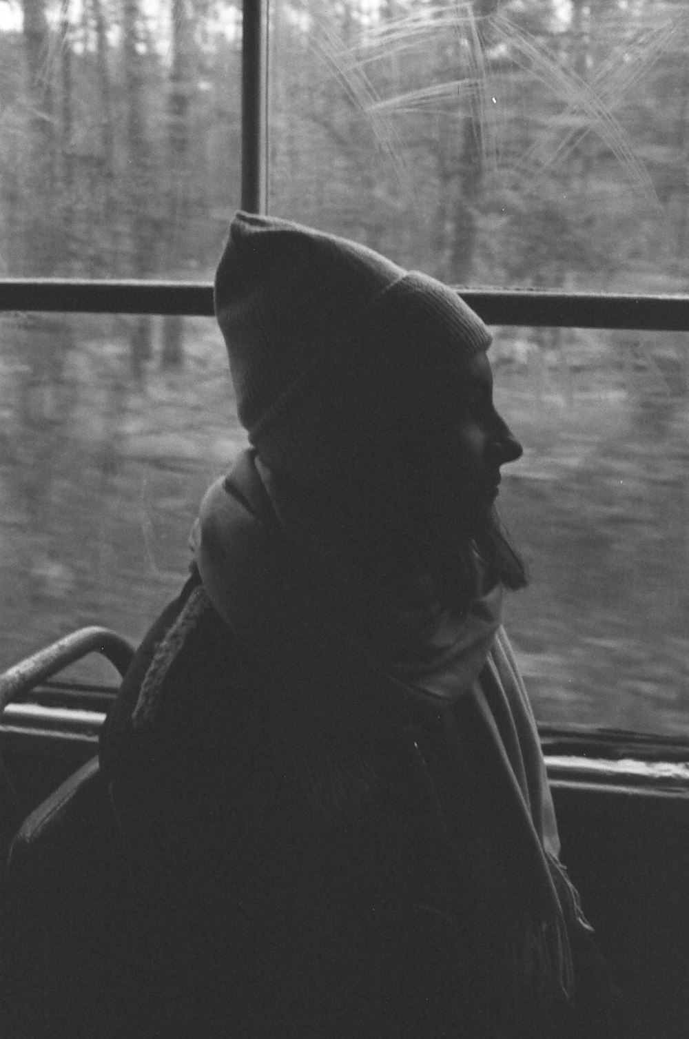 a black and white photo of a person looking out a window