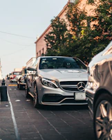 A row of luxury cars lined up on a city street, gleaming under soft daylight.