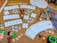 A collection of board game components and crafting materials are spread out on a cork board surface. There are playing cards, dice in various colors and sizes, wooden letter tiles spelling 'BOARDGAMES', 'DRAW', and 'WIN', colored buttons, a variety of markers and colored pencils, scissors, glue stick, and circular cardboard cutouts. The setting is vibrant and full of an assortment of gaming and crafting items.