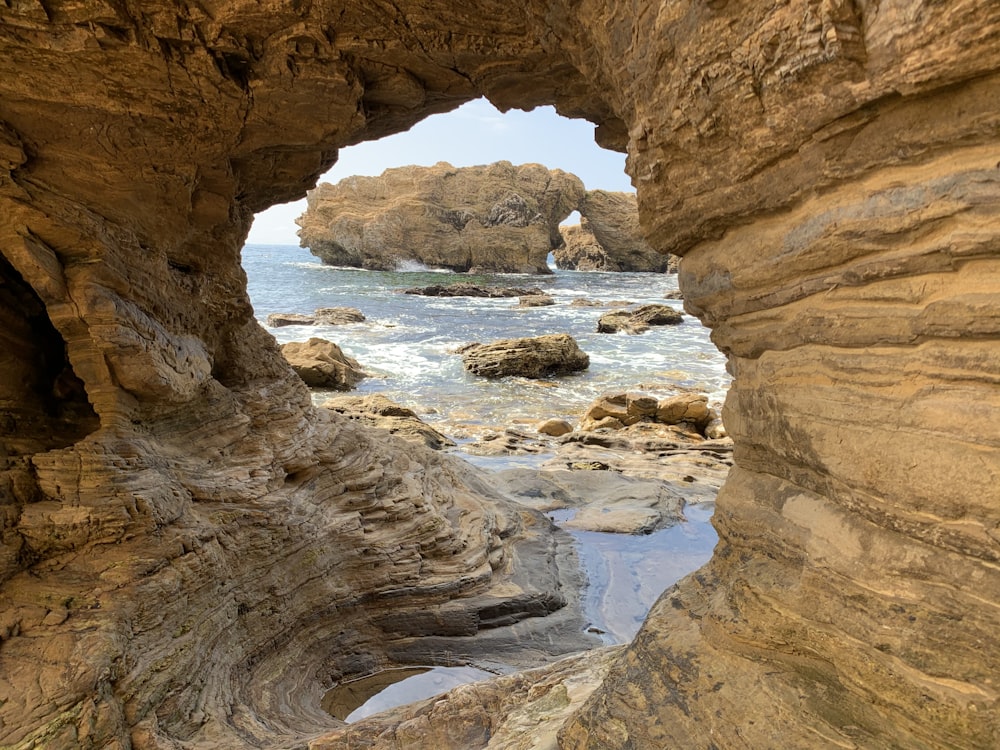 a view of a rocky beach through a hole in the rock