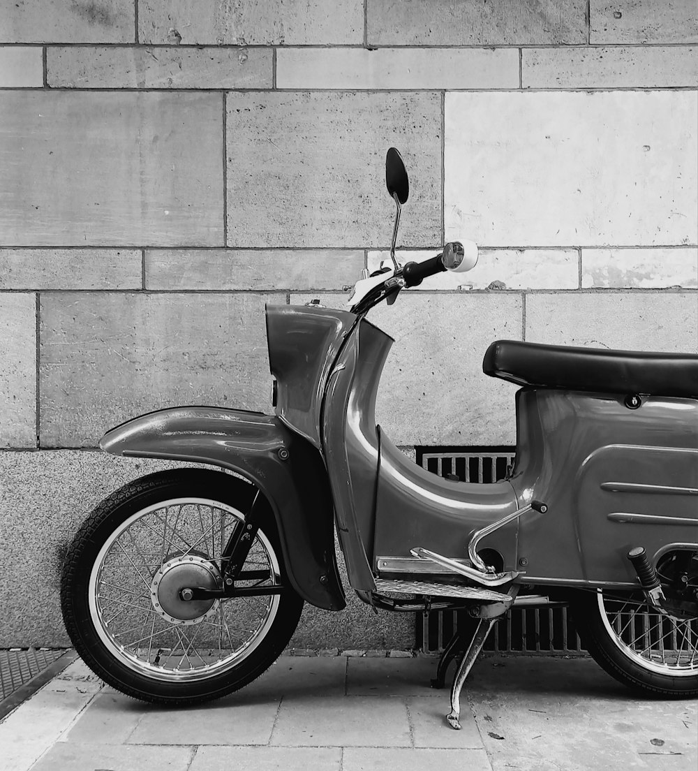 a motor scooter parked next to a brick wall