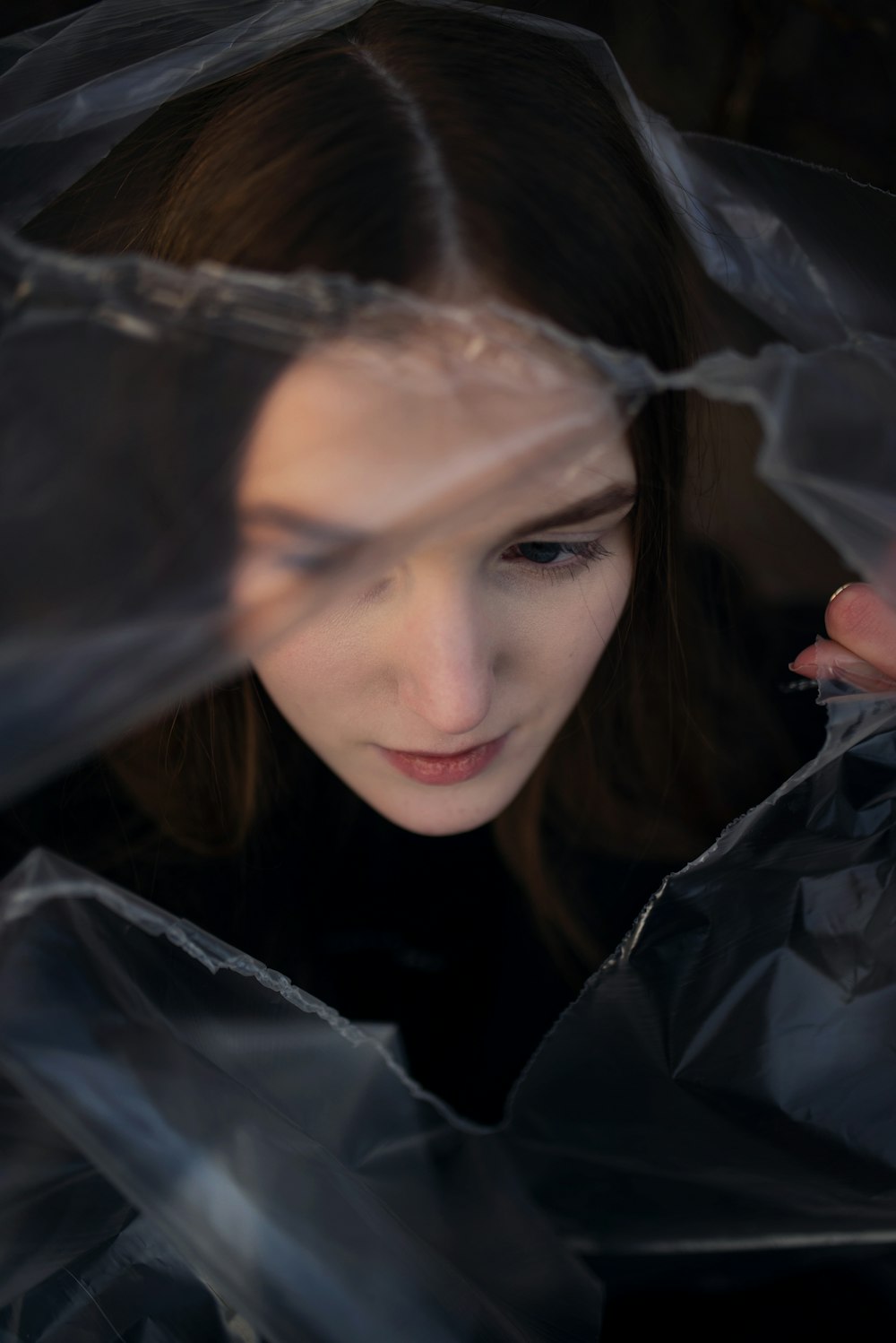 a woman in a plastic bag looking down at her cell phone