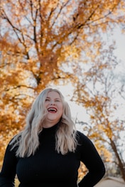 a woman standing in front of a tree with her hands on her hips
