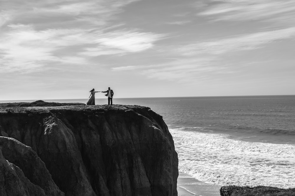 a couple of people standing on top of a cliff